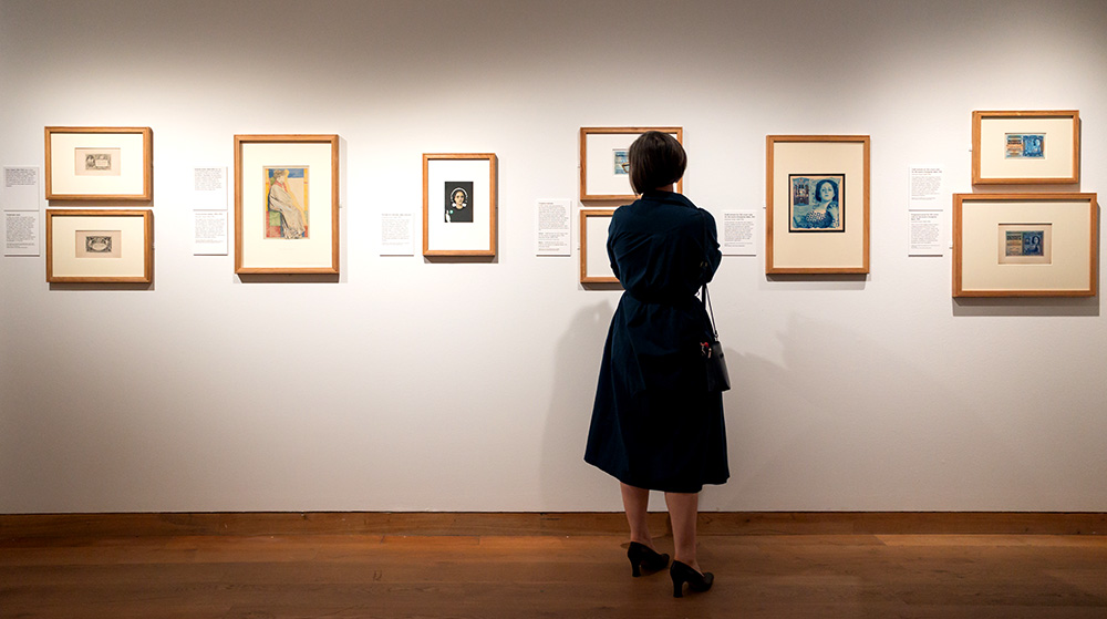 Visitor looking at the display of Swiss art nouveau banknote designs including sketches by Klimt and Moser in the Money Talks exhibition