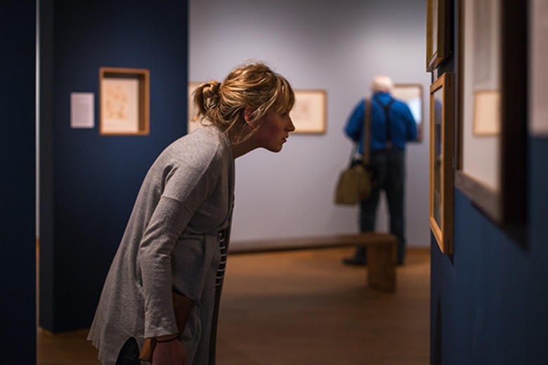 A woman looks at an artwork hanging on the wall of an art exhibition