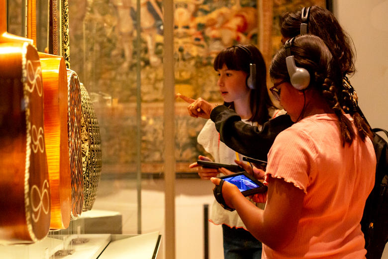 Family holding digital guides doing the Ashmolean Adventure in the Music gallery