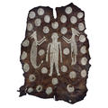 A large mantle or wall hanging made from animal hide and designed with small white shells forming images of a figure, animals and circles