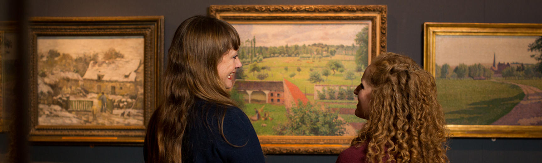 Two women looking at a Pissarro painting