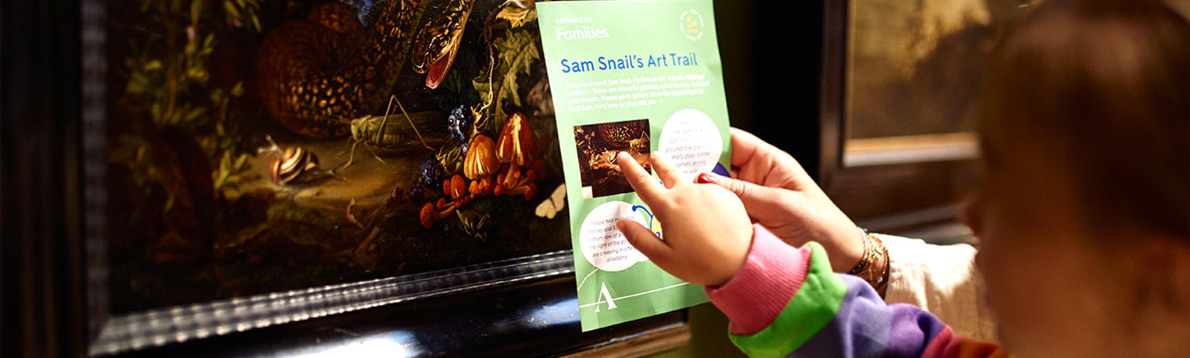 Children pointing at the Snail Trail tour leaflet in the galleries