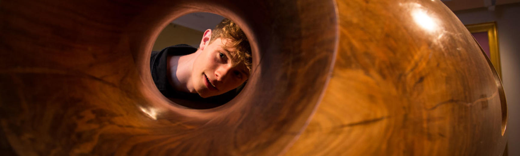 A young man looking through a hollow modern art work