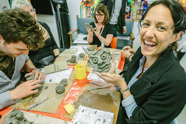Women holding up hand made clay face in education studio