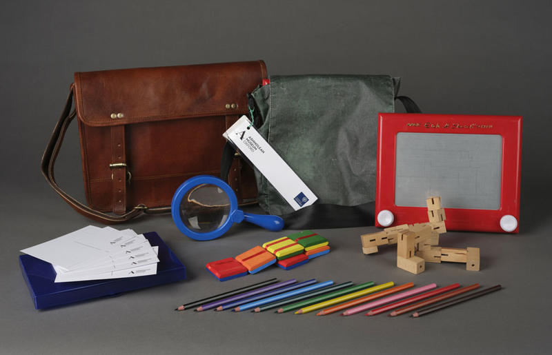 An activity pack and its contents, including pencils, an etch-a-sketch and a magnifying glass