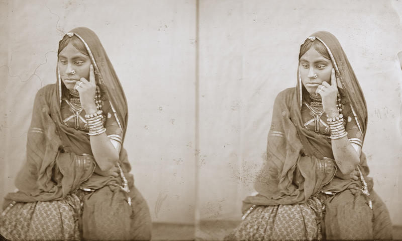 Black and white photograph of seated nautch girl, hand to veil