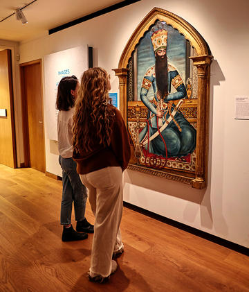 Inside the Images of Authority exhibition visitors looking at the sumptuous Shah of Iran portrait