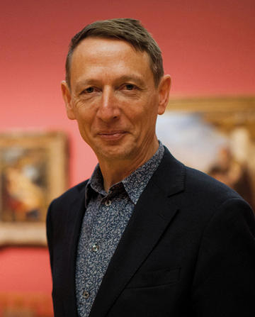 Photograph of Dr Xa Sturgis, the Ashmolean Museum Director, who is stood in a gallery of paintings